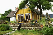 A wooden, yellow detached house with a terrace and a garden