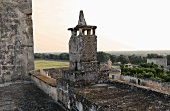 Weathered stone tower on a brick wall with a view of the Italian countryside