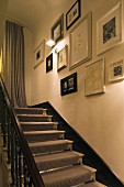 Stairway with ambient wall lighting with a striped stair runner and collection of pictures on the wall