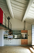 Open kitchen in a living room of a country home with a view of a white beam ceiling painted white and a mezzanine