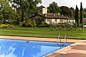 Poolecke mit Schwimmbadleiter und Blick auf Mediterraner Gehöft