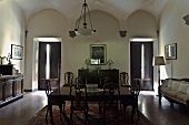 Vaulted ceiling in the darkened dining room of a villa with period furniture and windows with shutters