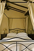Canopy bed with an elegant black metal frame and white bed linen