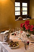 A festively laid table in a warm light with champagne in an ice bucket and small canapes on a plate