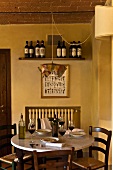 Esszimmerecke - Gedecke mit Rotwein auf rundem Marmortisch und Wandregal mit Weinlager