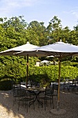 Sunny day -- garden chairs and table with a sun umbrella on a gravel patio
