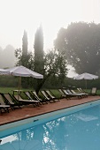 Foggy morning -- poolside with lounge chairs and sun umbrellas