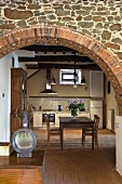 View through a brick archway into the kitchen of a country home with a dining area