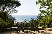 Terrasse mit schwarzen Rattanstühlen und Meeresblick