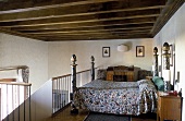Four poster double bed on a mezzanine under a beam ceiling in a country home