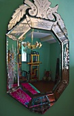Verzierter Spiegel an grüner Wand mit Spiegelung