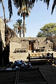 Benches on sand in the courtyard with lime walls and tall palm, Egypt