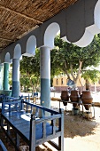 Blue benches under a straw roof with oriental architectural elements and view of clay planters, Egypt
