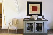 Vintage style gray cabinet with wire mesh doors and white Rococo chairs in an anteroom