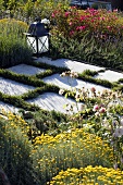 Section of a garden -- stone pavers edged with grass illuminated by a lantern