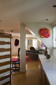 Converted attic with a white column and view of a leather couch in a open living room