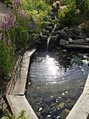 Teich in Holzeinfassung und Wasserzulauf im Garten