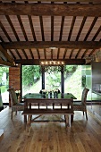 Renovated country home - dining area under a beam ceiling with a designer pendant lamp in front of terrace windows