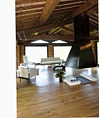 Renoviertes Landhaus mit rustikaler Holzbalkendecke und offenem Kamin mit schwarzem Abzug und helle Designer Sitzmöbel