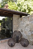 A set of three candles in large round metal grill work holders in the corner of the terrace of a country home