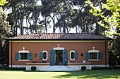 Mediterranean villa with a red brick facade and blue-gray shutters in a garden