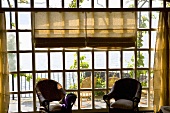 Sunny day - wicker chairs in front of lattice windows with a view of a terrace and the ocean