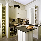 Hellgraue Einbauküche im eleganten Landhausstil und quadratischer Küchenblock mit schwarzer Arbeitsplatte