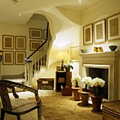 Atmospheric lighting in a living room of a villa with a flight of stairs and white flowers in pots standing in front of the fireplace