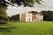 Ballinlough Castle Gardens - Wiesenfläche vor irischer historischer Schlossanlage teilrenoviert mit Ecktürmen und Zinnen