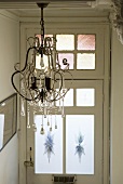 A chandelier with beads and glass droplets in the hallway of an old residential house