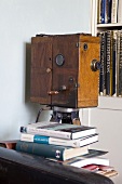 Antique film camera in a wooden case in front of a book shelf