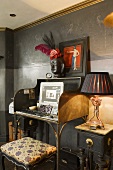 A home office set up on an antique davenport against a black wall with a stool in front of it
