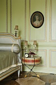 A bedroom with green wood panelling and gilded borders and an old drum being used as a bedside table