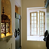 A hallway in a rustic country house - oriental lanterns in a wall niche and an open transom window