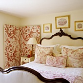 An antique double bed with a padded headboard and gold framed pictures