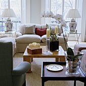 A modern wooden coffee table and a light, upholstered sofa in front of floor-to-ceiling windows