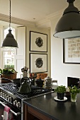 Metal lampshades above a kitchen counter and a cooker in an open plan kitchen in a country house