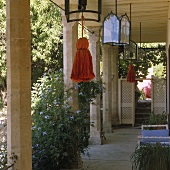 A terrace with stone pillar and lanterns with coloured tasssels hanging from the ceiling