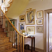 Alte Holztreppe und Bildersammlung über Wandtisch im Treppenraum eines Landhauses