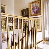 A view through a wooden banister in a stairway with pictures on the wall