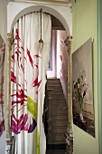 A flower pattern on a curtain in an archway to a stairwell