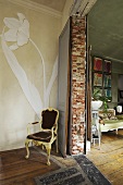 Durchgesessener Stuhl und gemalte Blume auf Wand neben Durchgang mit Blick in Wohnraum