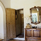 Wohnraum mit offenstehender Zimmertür und antikem Sideboard mit Spiegel