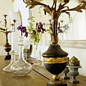 A glass carafe and an antique candlestick on a wooden shelf