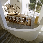 A view onto an oval-shaped living room with a rustic table and designer chairs