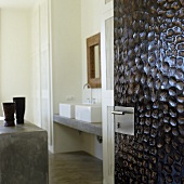 A view through an open door with a structured surface onto a counter and a concrete wash basin