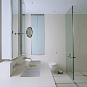 A light-coloured washstand with a mirrored cabinet and a glass partition wall
