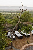 Loungers on a wooden terrace with bamboo umbrella and view of the South African landscape