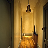 Beleuchteter Flur mit grauen Zimmertüren und schmaler Holzablage