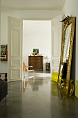 An access room in a period building with a reflective concrete floor and a gold framed mirror leaning against the wall